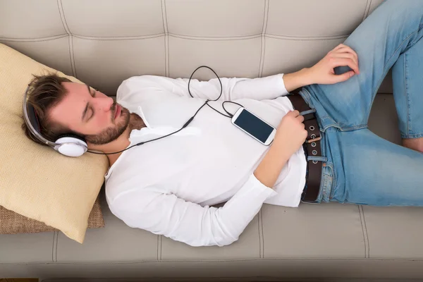 Young man listening to music on the sofa — Stock Photo, Image