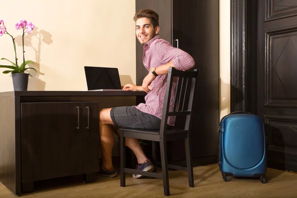 Ung man använder en bärbar dator i en asiatisk inredda hotellrum — Stockfoto