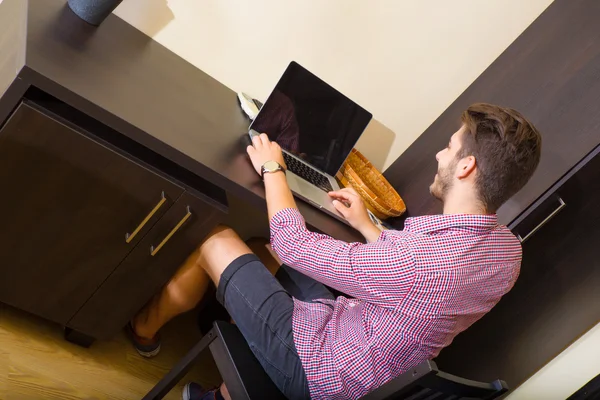 Jovem usando um computador portátil em um quarto de hotel estilo asiático — Fotografia de Stock