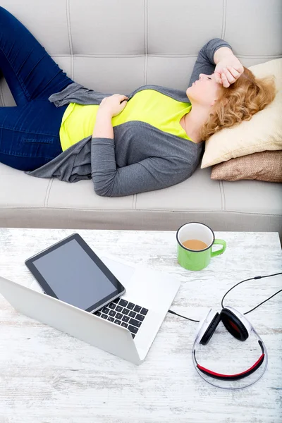 Junge Frau auf dem Sofa mit Gadgets — Stockfoto