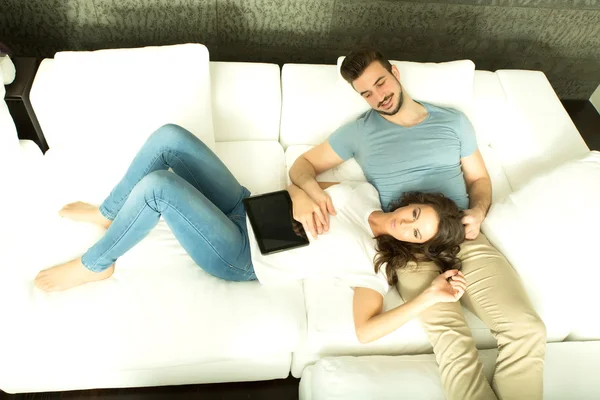 Jeune couple utilisant une tablette PC ensemble sur le canapé à la maison — Photo