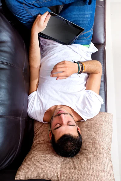 Jovem macho com tablet em um sofá — Fotografia de Stock