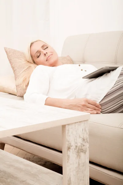Mujer durmiendo con la tableta en el sofá —  Fotos de Stock