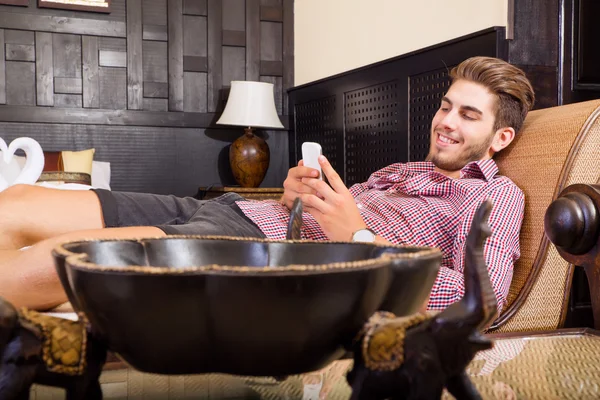 Young man in a hotel room using a phone — Stock Photo, Image