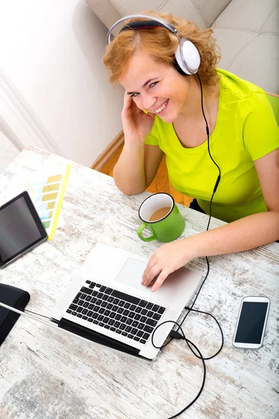 Junge Plus-Size-Frau hört Audio, während sie an einem Lapt arbeitet — Stockfoto