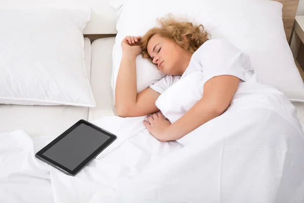 Młoda kobieta spanie w łóżku z komputera typu Tablet — Zdjęcie stockowe