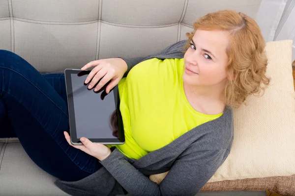 Mujer joven relajándose con una tableta PC en el sofá —  Fotos de Stock