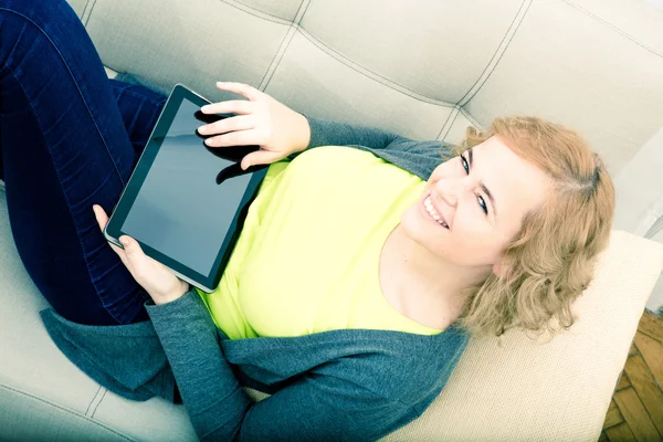 Mujer joven relajándose con una tableta PC en el sofá — Foto de Stock