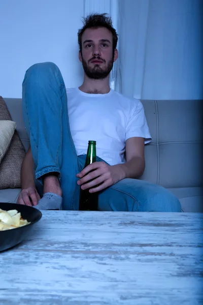 Młody człowiek oglądać Tv w nocy z frytkami i piwo — Zdjęcie stockowe