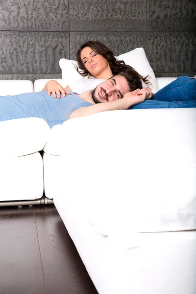 Mladý pár, mazlení na gauči doma — Stock fotografie