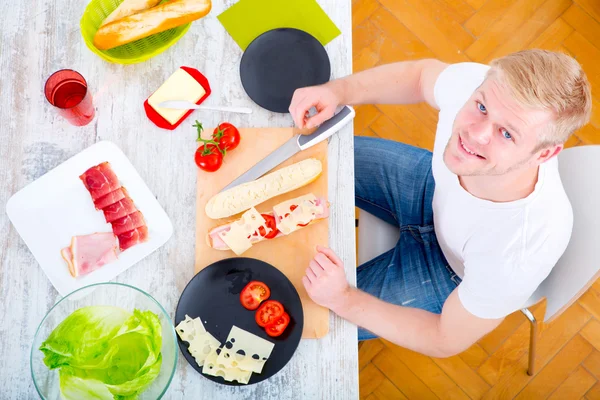 Jongeman bereidt een broodje voor — Stockfoto