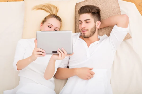 Jeune couple avec une tablette PC au lit — Photo