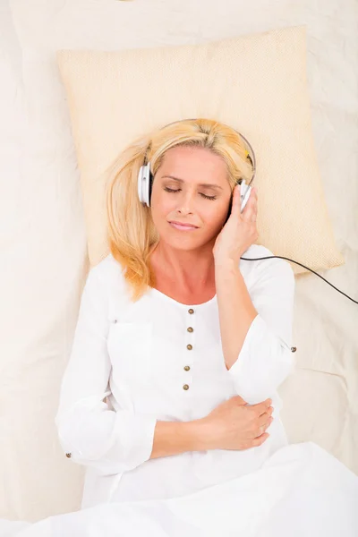 Vrouw met hoofdtelefoon en tablet in bed — Stockfoto