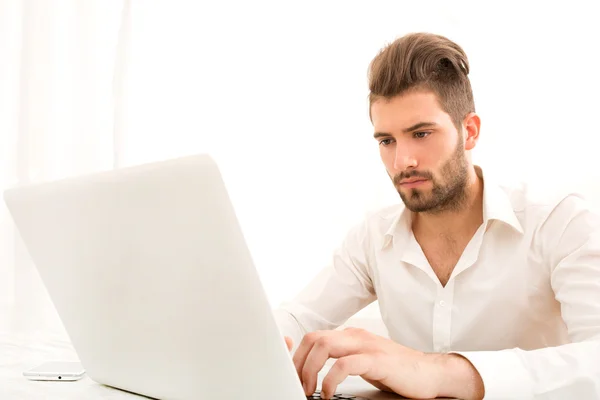 Jovem macho em casa com um laptop — Fotografia de Stock