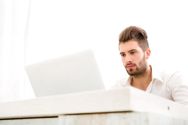 Tânăr bărbat acasă cu un laptop — Fotografie, imagine de stoc