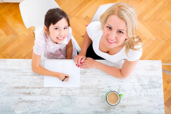 Moeder haar dochter met het huiswerk helpen — Stockfoto