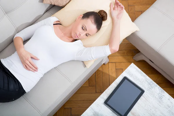 Jeune femme avec une tablette PC sur le canapé — Photo