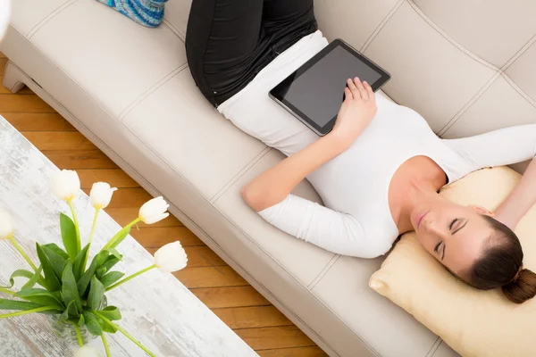 Mujer joven con un Tablet PC en el sofá — Foto de Stock