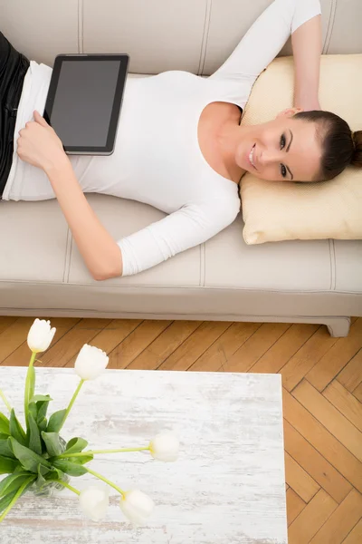 Ung kvinna med en TabletPC i soffan — Stockfoto