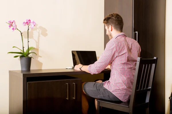 Jovem usando um computador portátil em um quarto de hotel estilo asiático — Fotografia de Stock