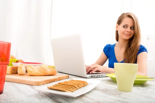 Jonge vrouw met behulp van een laptop na het ontbijt — Stockfoto