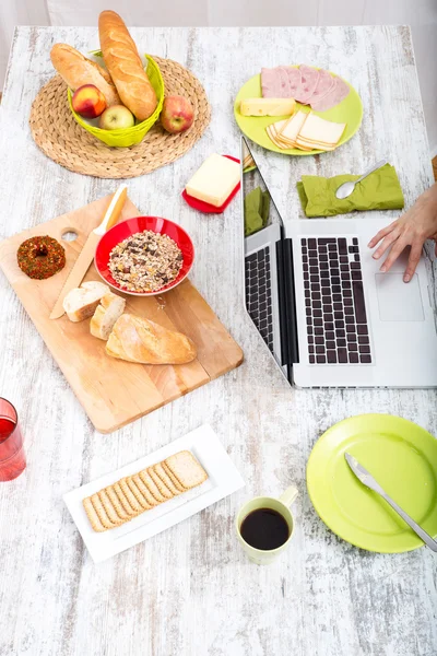 Giovane donna che fa colazione mentre utilizza un computer portatile — Foto Stock