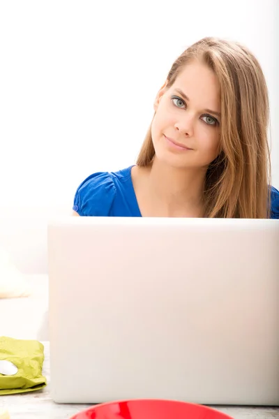 Young woman having breakfast while using a laptop computer — Stock Photo, Image