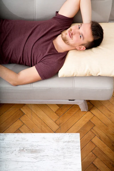 Jeune homme couché sur le canapé — Photo