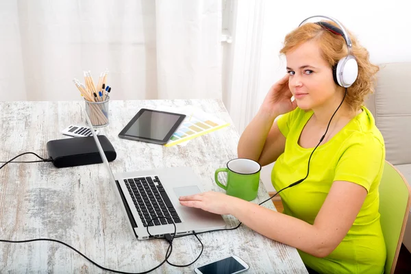 Unga plus size kvinna lyssna på ljud medan du arbetar på en lapt — Stockfoto