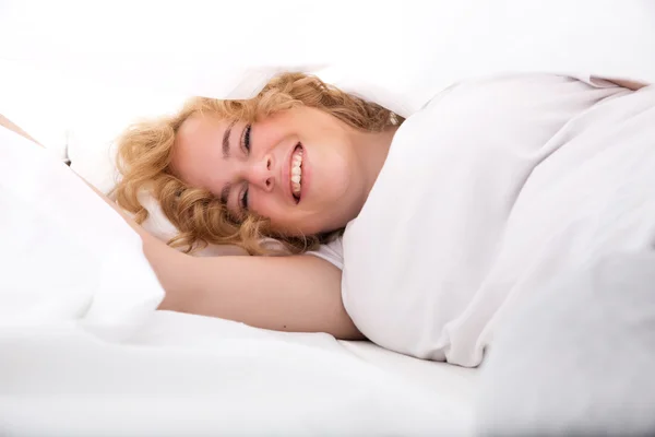 Mujer joven escondida en la cama debajo de las sábanas — Foto de Stock