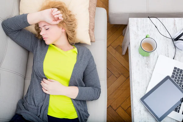 Jonge vrouw op de bank met gadgets — Stockfoto