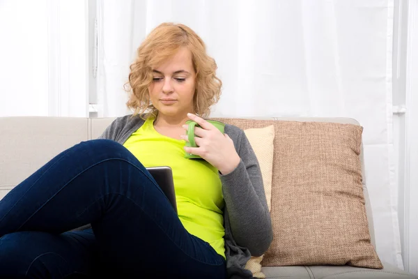 Mujer joven con un Tablet PC en el sofá —  Fotos de Stock