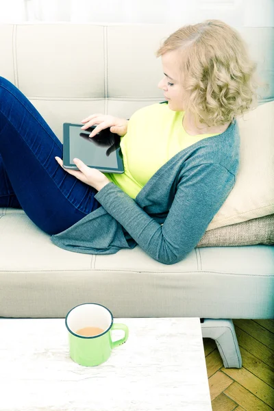 Mujer joven relajándose con una tableta PC en el sofá — Foto de Stock