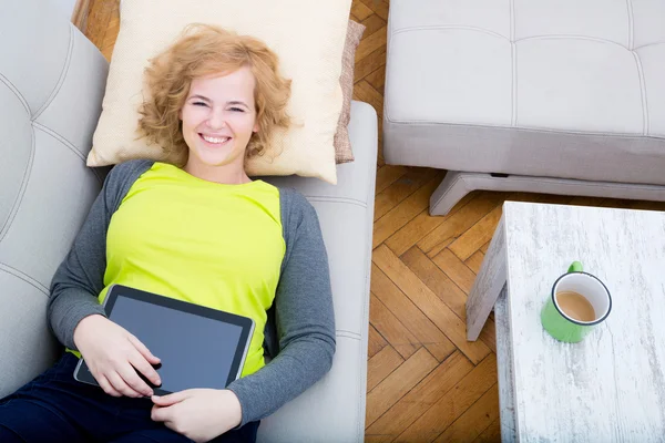女人放松与 Tablet Pc 在沙发上 — 图库照片