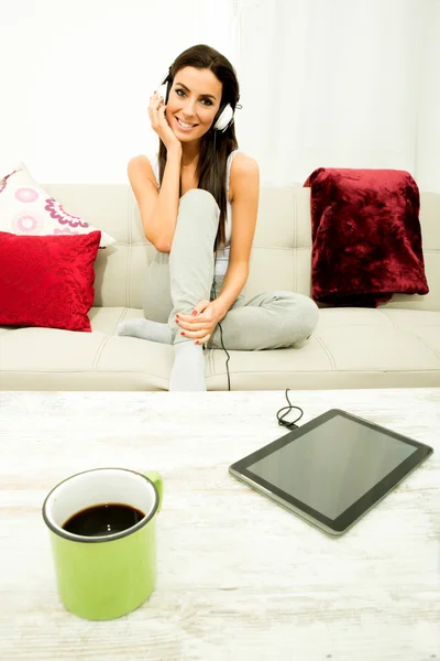 Jovem bela mulher ouvindo música com um Tablet PC no hom — Fotografia de Stock