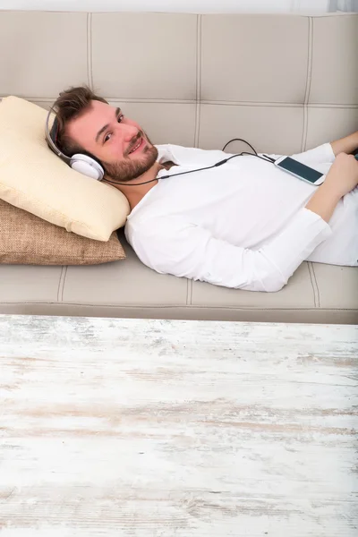 Ung man lyssnar på musik i soffan — Stockfoto