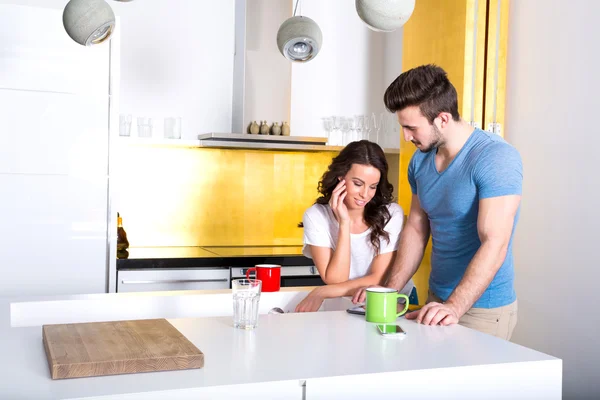 Pareja joven usando un Tablet PC en la cocina en casa —  Fotos de Stock