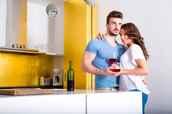 Pareja joven bebiendo vino en la cocina —  Fotos de Stock