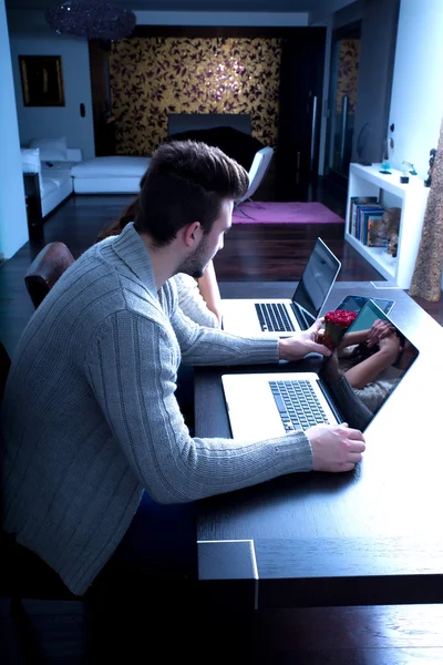 Casal jovem na frente de seus computadores portáteis em casa — Fotografia de Stock