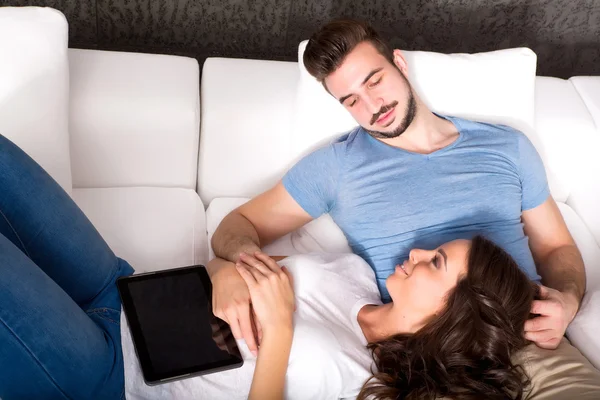 Young couple using a Tablet PC together on the Sofa at home — Stock Photo, Image