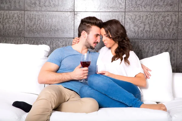 Hermosa pareja disfrutando de una copa de vino en el sofá — Foto de Stock