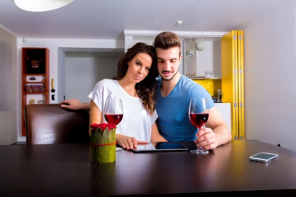 Pareja joven usando un Tablet PC mientras toma una copa de vino — Foto de Stock