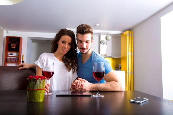 Casal jovem usando um Tablet PC enquanto toma um copo de vinho — Fotografia de Stock