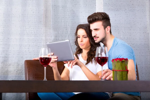 Casal jovem usando um Tablet PC enquanto toma um copo de vinho — Fotografia de Stock