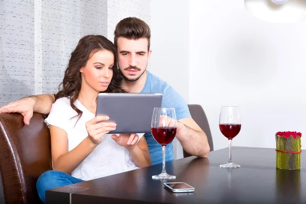 Νεαρό ζευγάρι χρήση Tablet Pc ενώ έχοντας ένα ποτήρι κρασί — Φωτογραφία Αρχείου