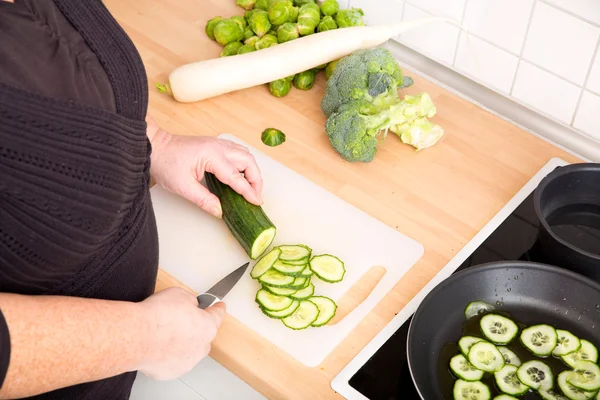 Woman cutting cucumber — Stock Photo, Image