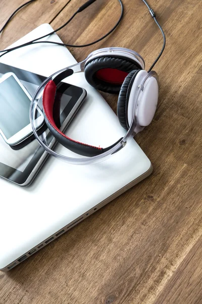 Dispositivos digitales y auriculares en un escritorio de madera —  Fotos de Stock