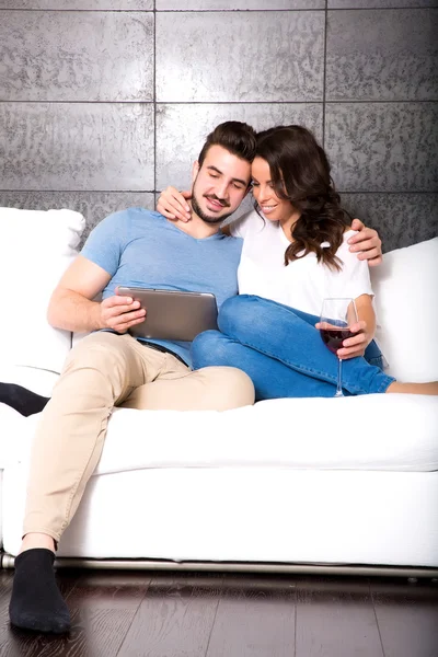 Young couple using a Tablet PC together on the Sofa at home — Stock Photo, Image