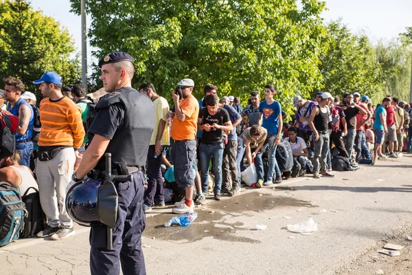 Policía vigilando la cola de espera de los refugiados en Tovarnik — Foto de Stock