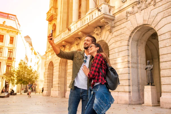 Um casal feliz tomando uma selfie enquanto passeia por uma cidade europeia — Fotografia de Stock